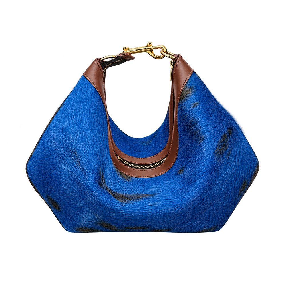 Royal blue hair-on-hide shoulder bag with black patches, brown leather trim, gold-tone zipper, and navy interior lining.